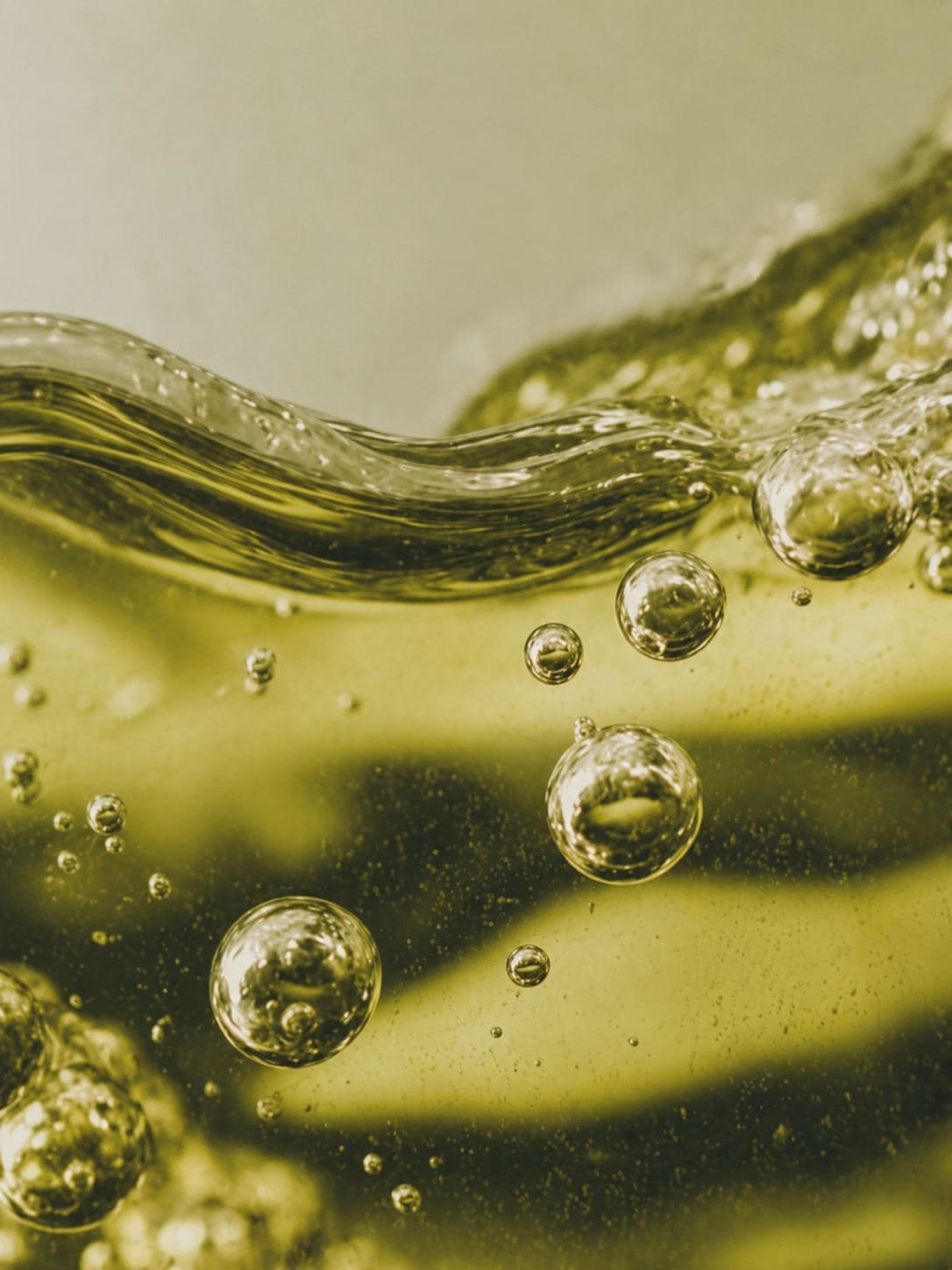A close-up of olive-green liquid with bubbles rising through it