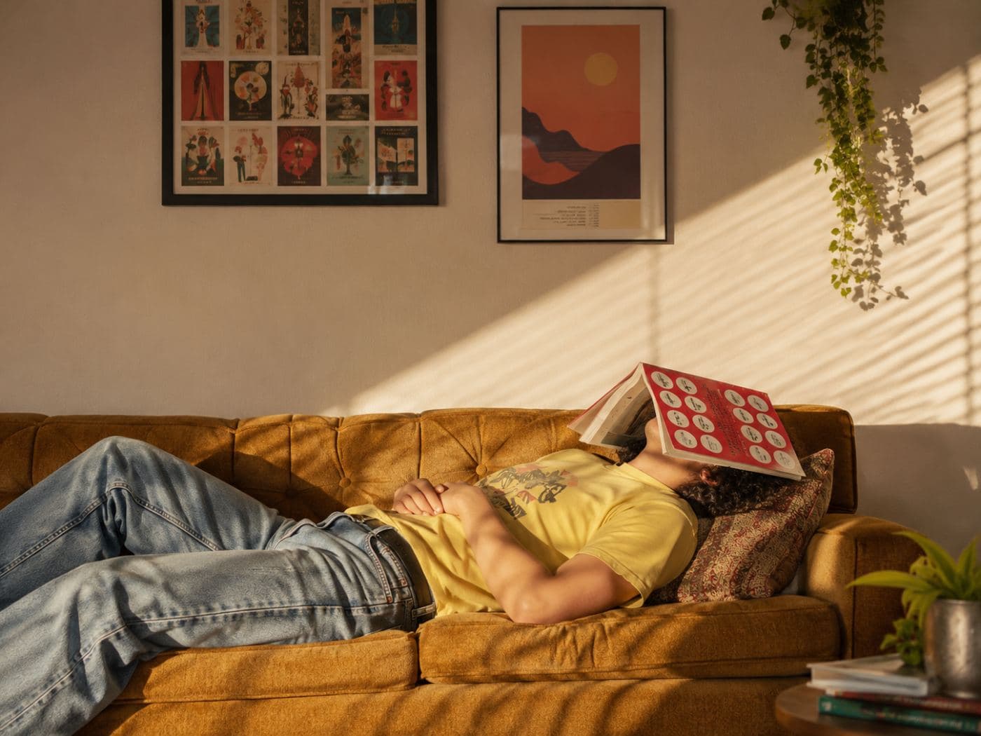 A man lying on a sofa with a cushion over his face in afternoon light