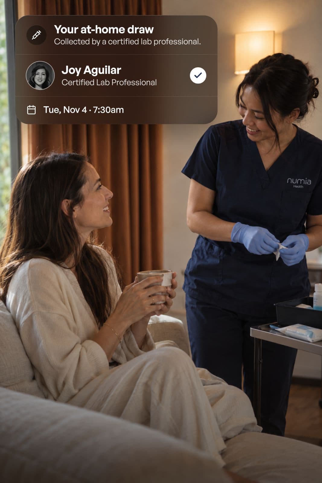 A Numia certified lab professional, Joy Aguilar, greeting a woman at home, with an at-home draw confirmation for Tue, Nov 4 at 7:30am