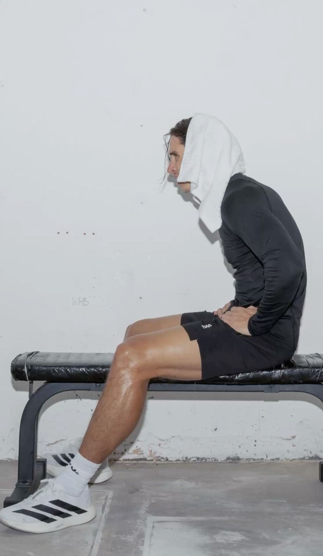 A person in a hooded top resting on a bench after training