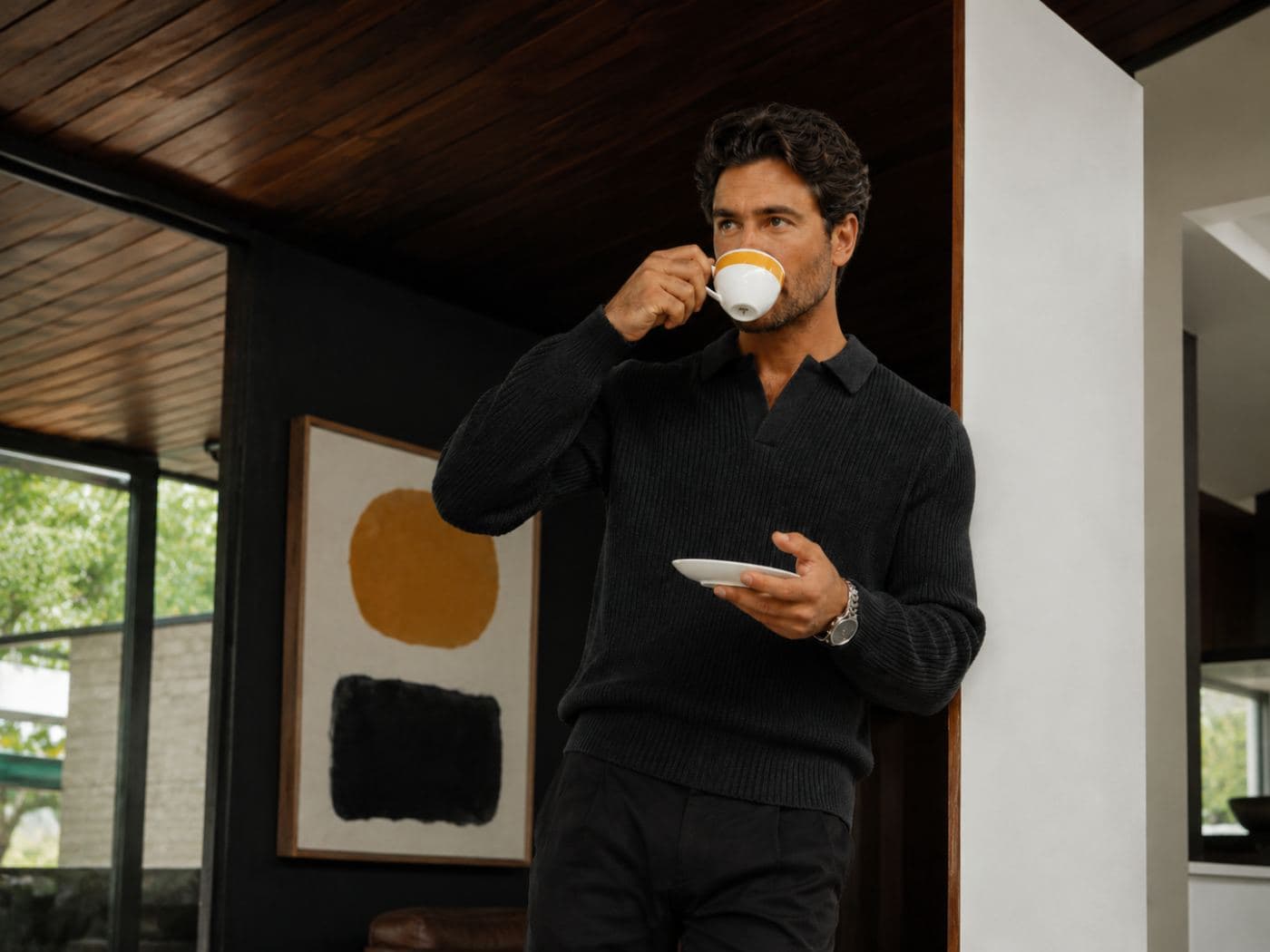 A man drinking an espresso in a sunlit living room